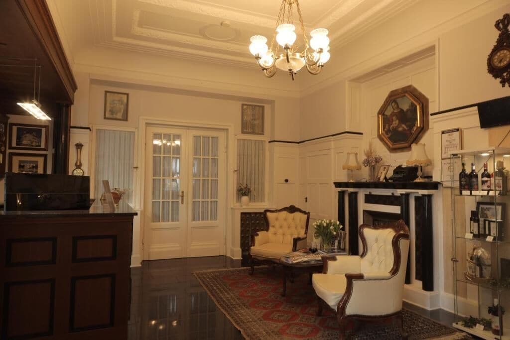 A room with a fireplace, two armchairs, a coffee table, and a chandelier.
