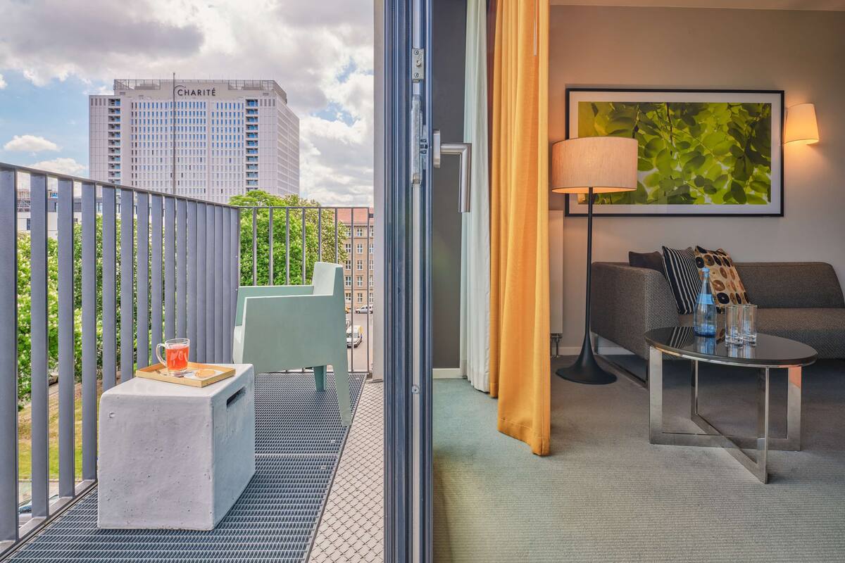Ein Balkon mit einem Betontisch, einem Metallstuhl und einem Glas Orangensaft.