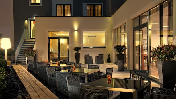 An outdoor seating area with wicker furniture and potted plants. - Adina Apartment Hotel Berlin Mitte (Berlin)