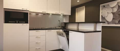 Una cocina moderna con armarios blancos, horno empotrado y lavavajillas.