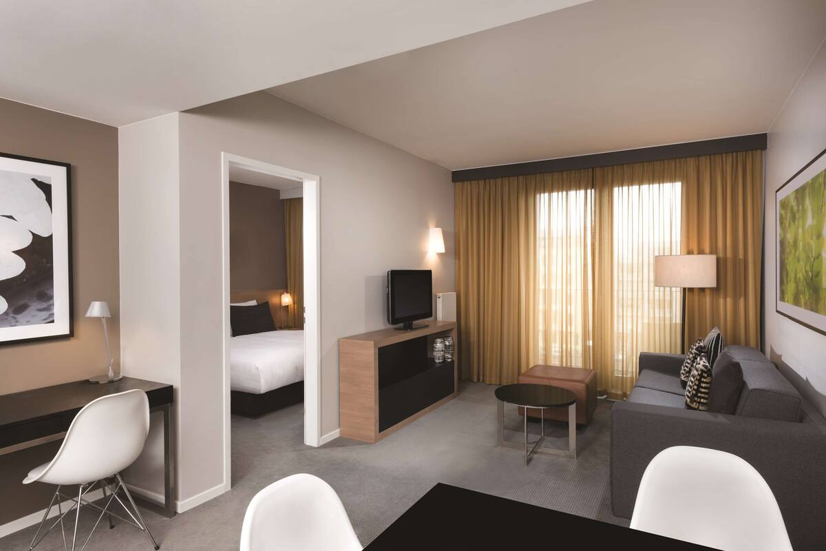 Ein Hotelzimmer mit Bett, Fernseher, Schreibtisch, Sofa und Essbereich.