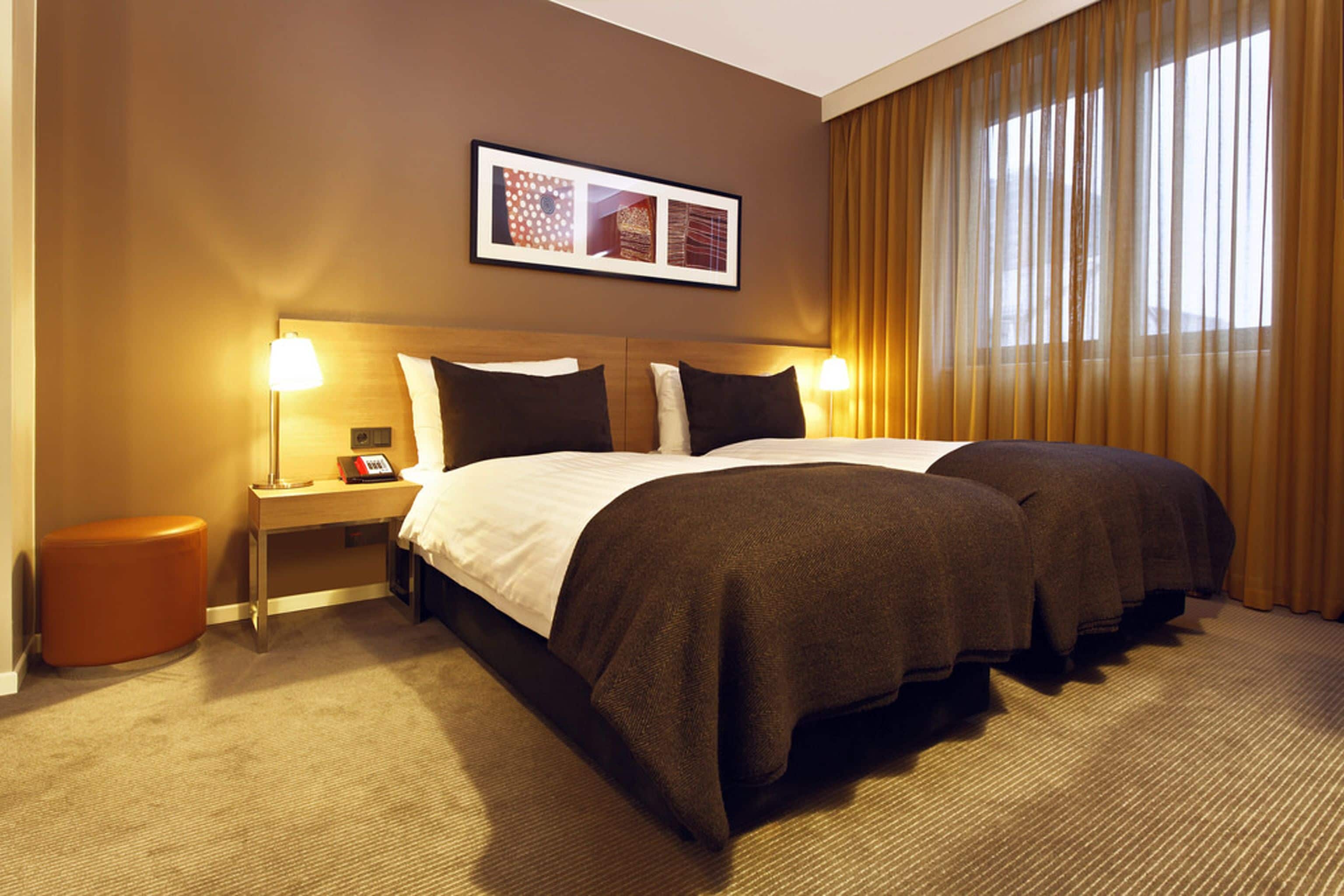 A hotel room with a large bed, two bedside tables, a nightstand, and a framed picture on the wall.