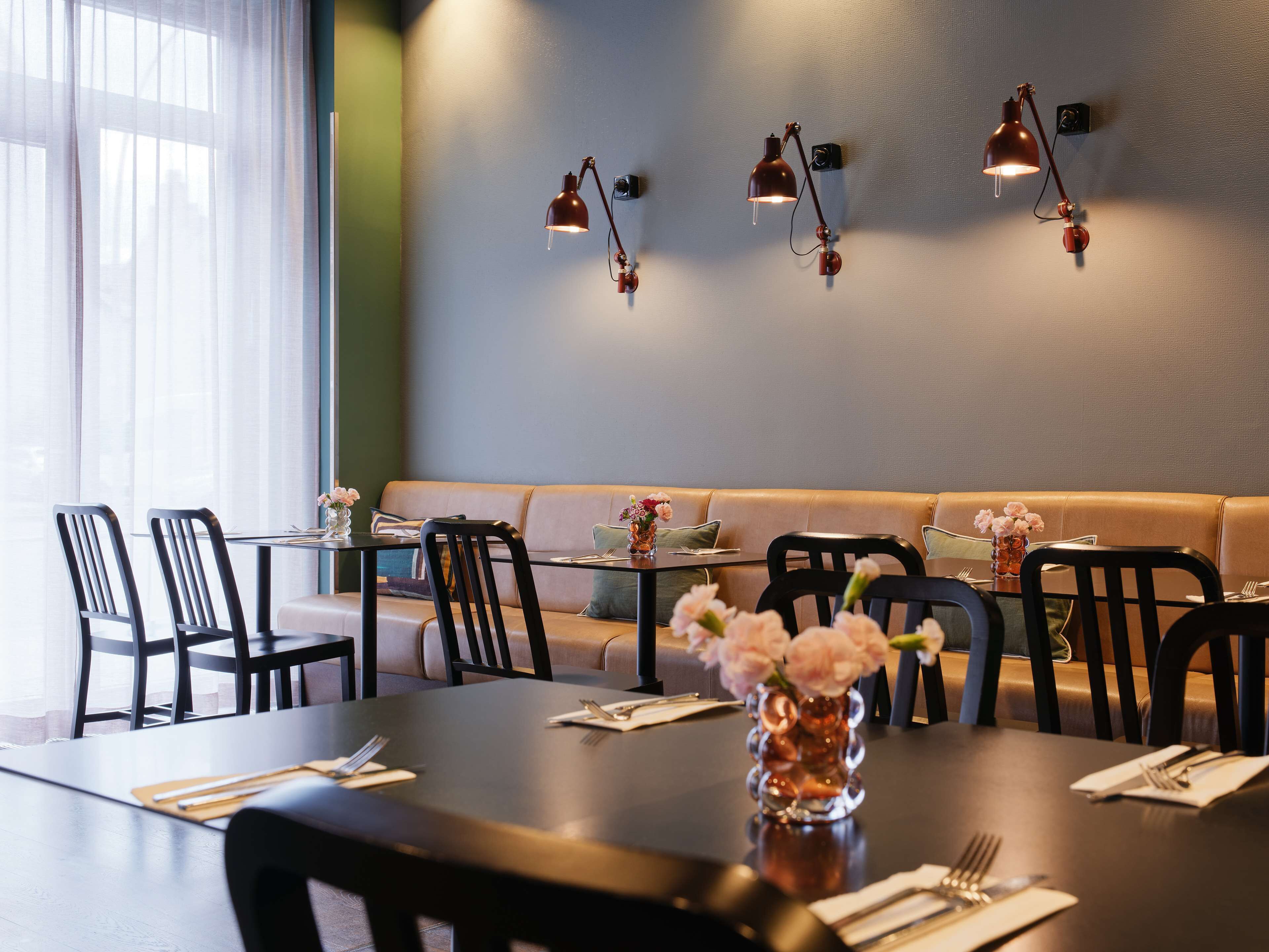 Een eethoek met een lange tafel, stoelen, een bank en wandlampen.
