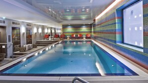 A large indoor swimming pool with a tiled wall and a staircase leading to upper levels. - Adina Apartment Hotel Berlin Mitte (Berlin)