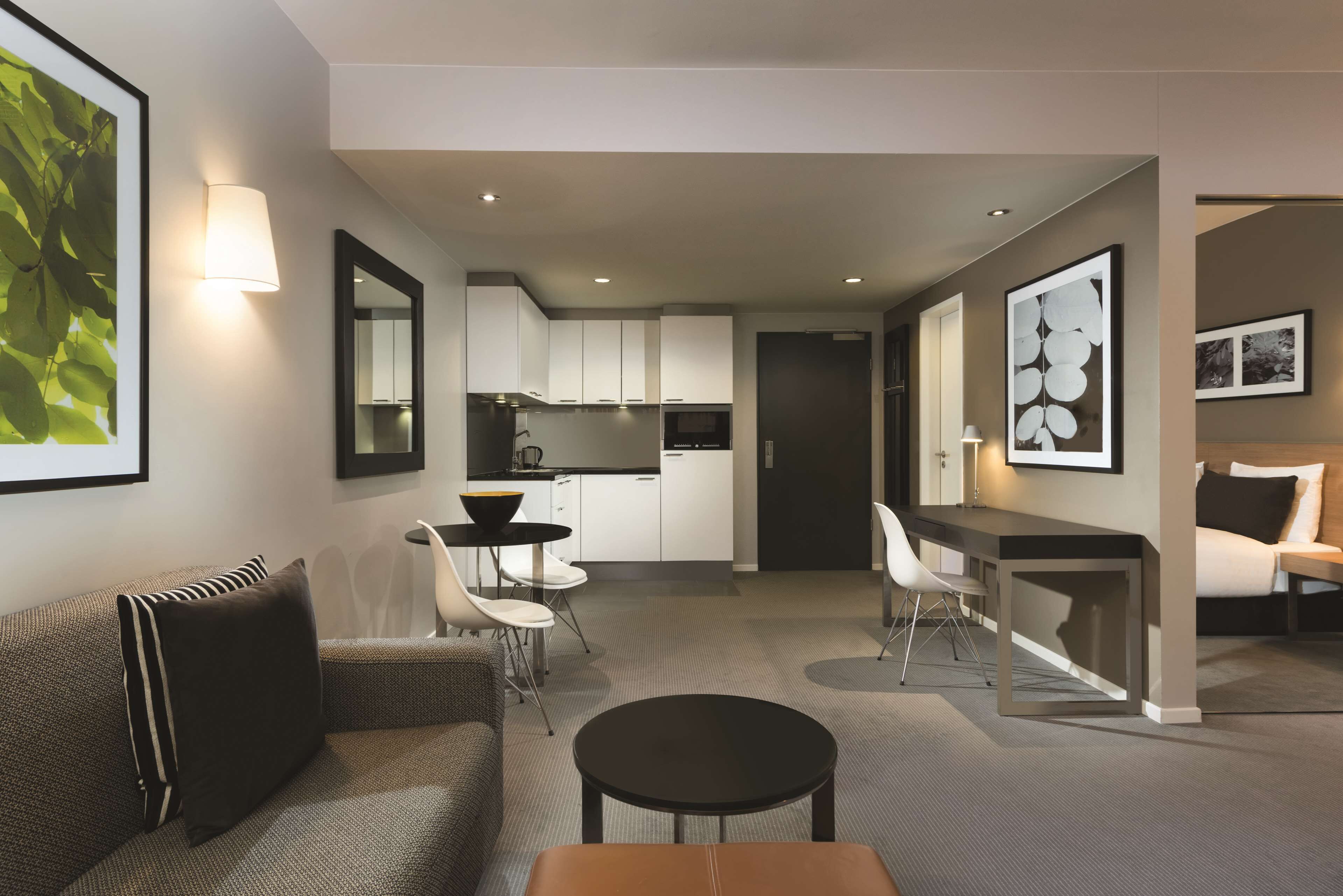 A modern living room with a sofa, a round coffee table, and a dining area with a small table and chairs.