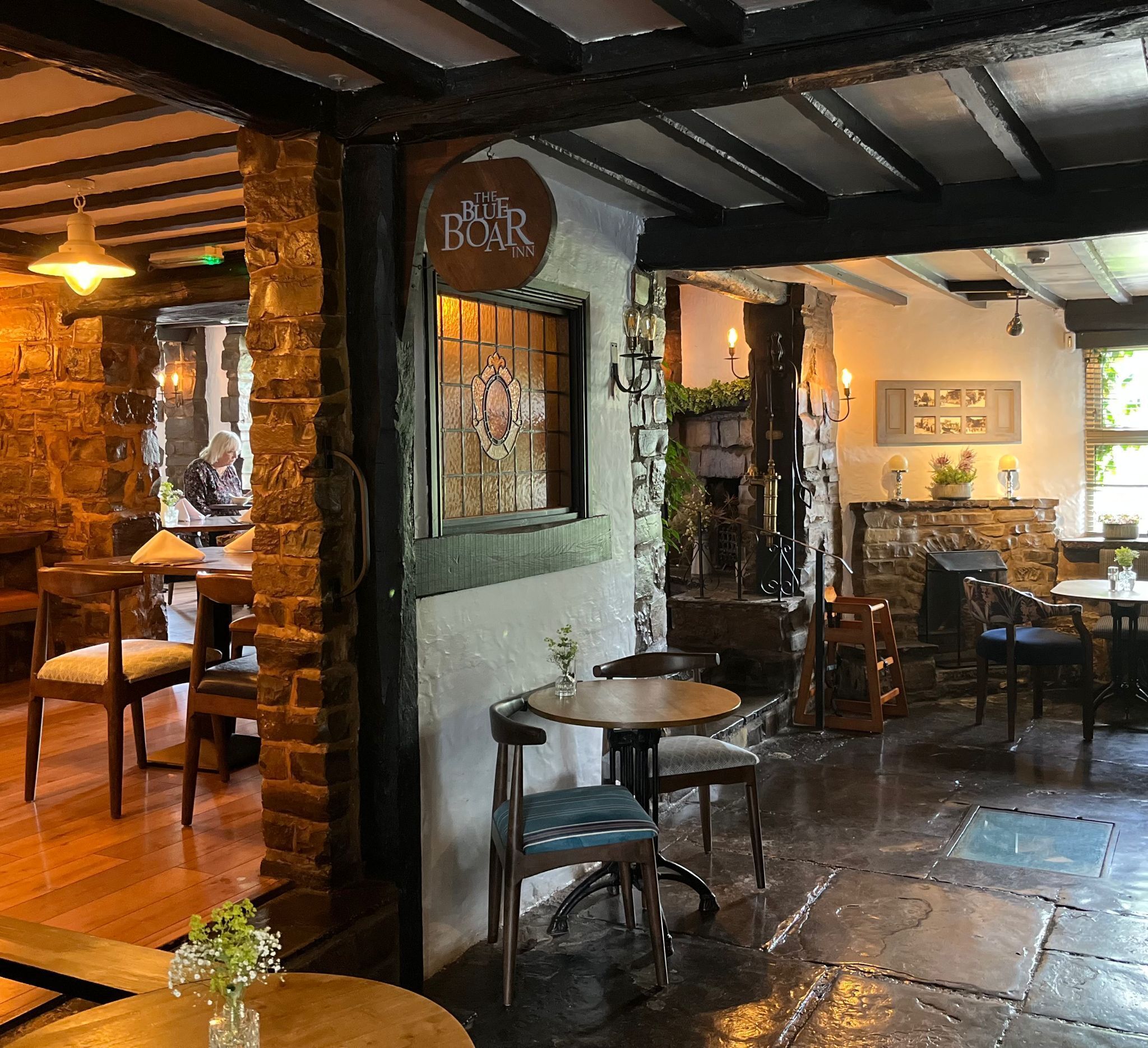 A cozy interior with stone walls, wooden furniture, and a sign reading "The Blue Boar Inn".