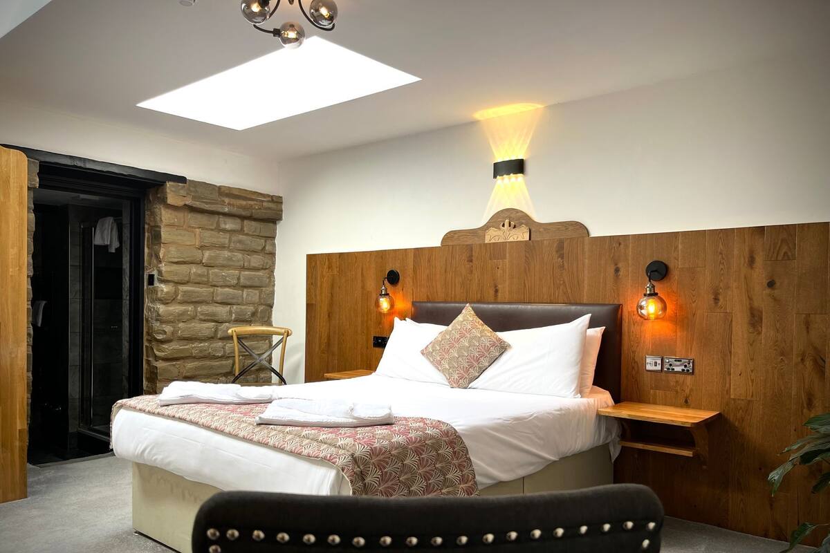 A modern bedroom with a large bed, a wooden headboard, and a skylight.