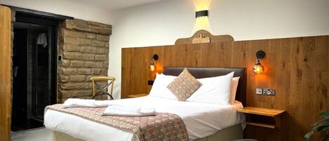 A modern bedroom with a large bed, a wooden headboard, and a skylight.