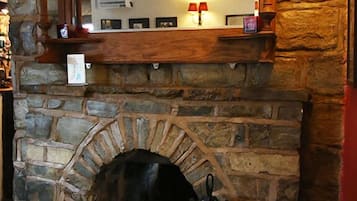 A stone fireplace with a wooden mantel, a mirror above it, and a small shelf with decorative items.