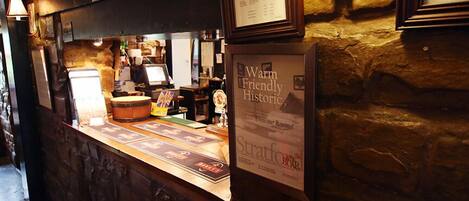 A bar area with a stone wall, a framed menu, and a sign indicating a fire exit.