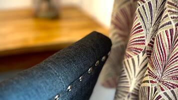 A close-up of a chair with a dark fabric and metal studs, and a patterned fabric draped over it.