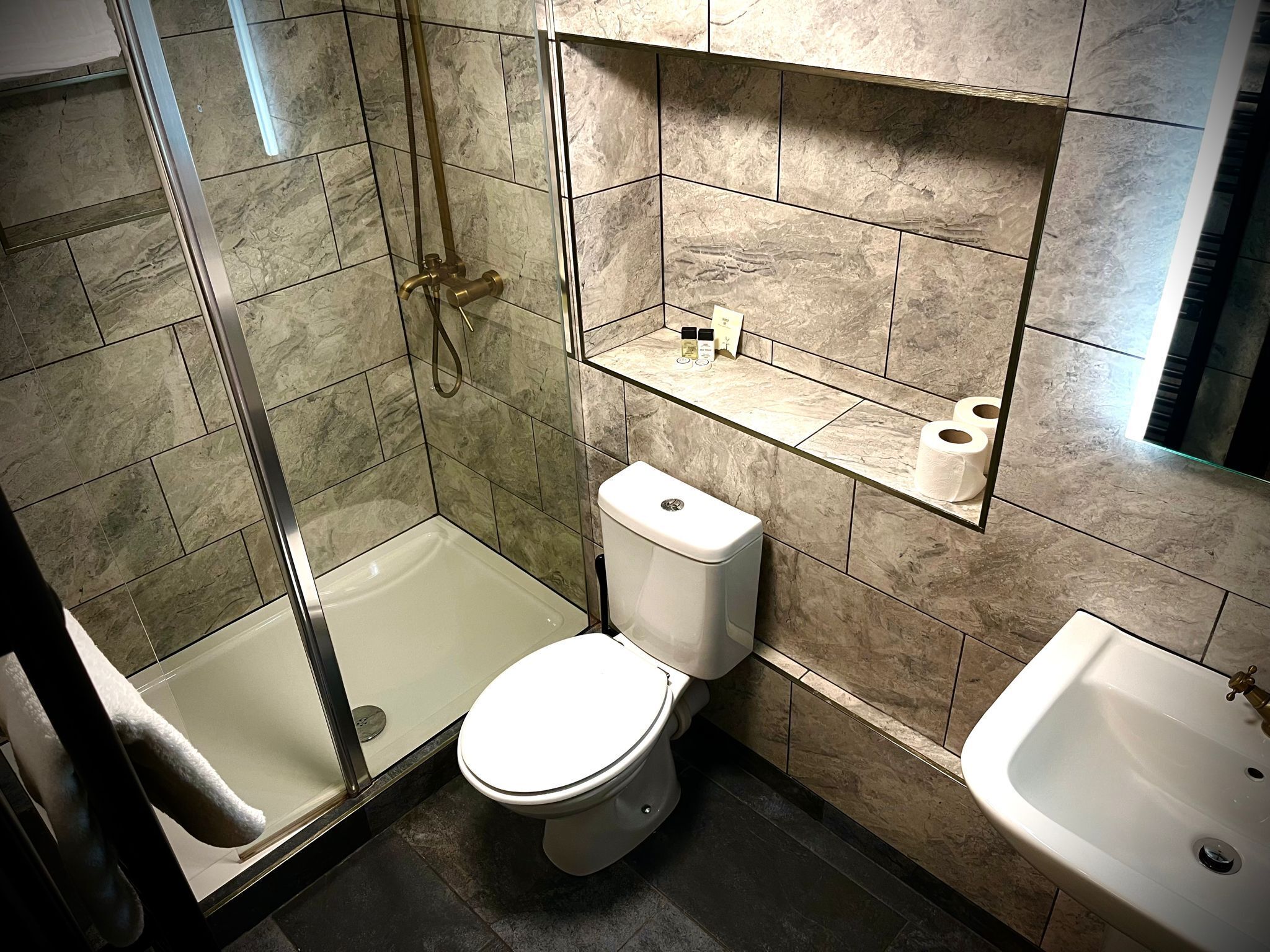 A bathroom with a glass-enclosed shower, a toilet, and a sink.