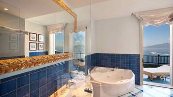 Ein Badezimmer mit einer großen Badewanne, einer Duschkabine aus Glas und Meerblick vom Balkon aus.