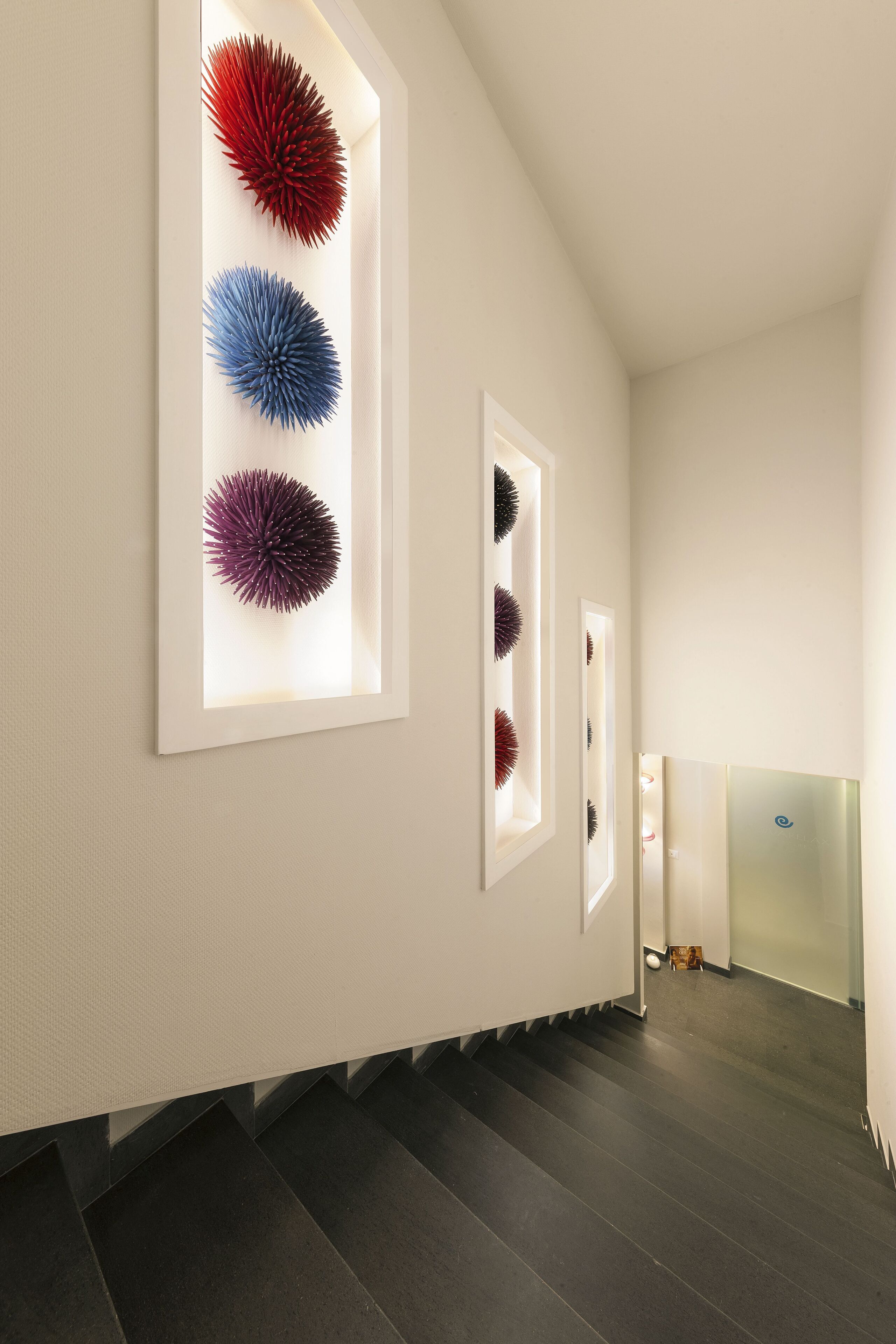 A modern interior with a staircase, framed wall art, and a glass partition.