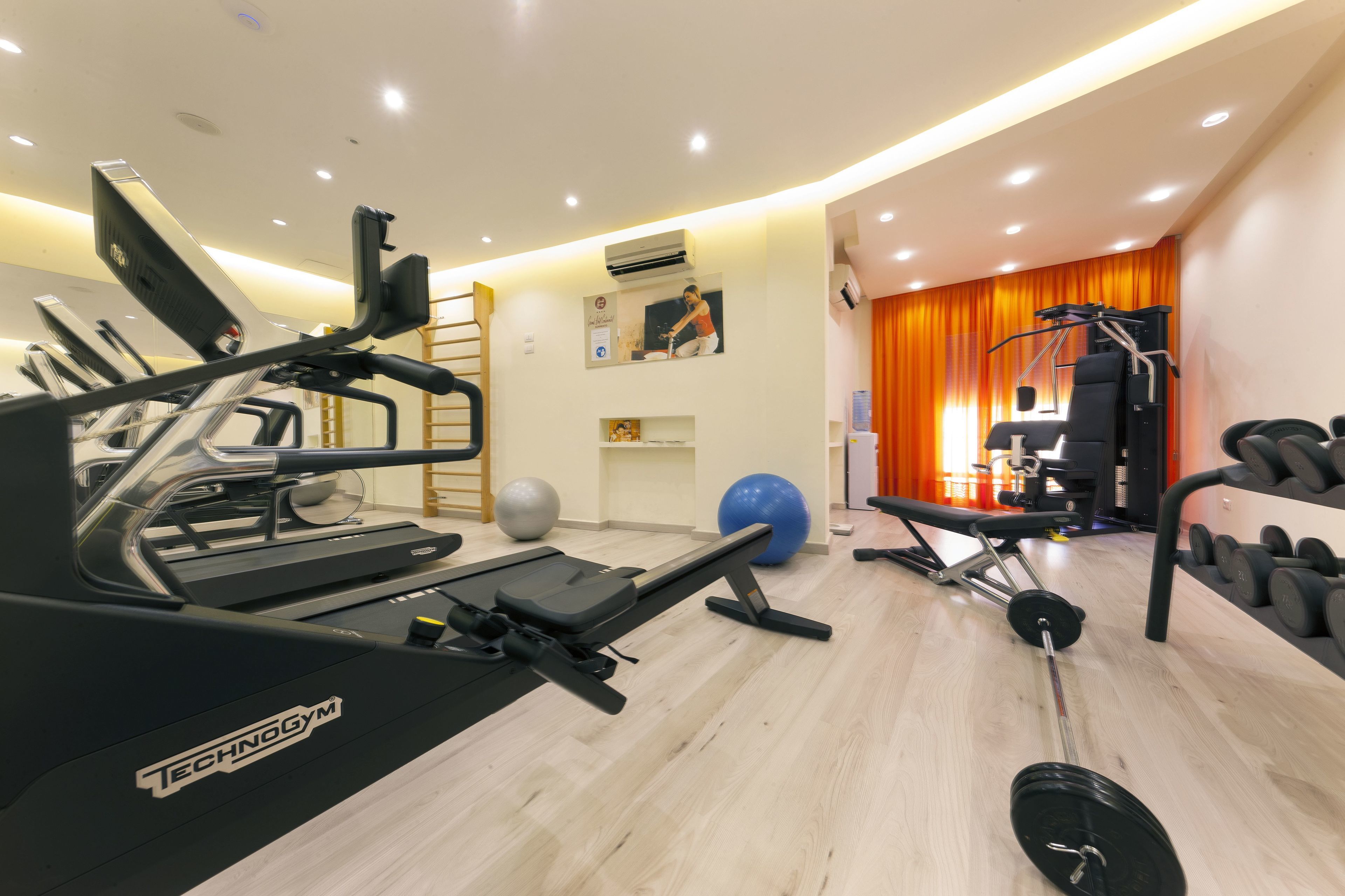 Et fitnessrum med løbebånd, bænkpres og en squat-stativ.