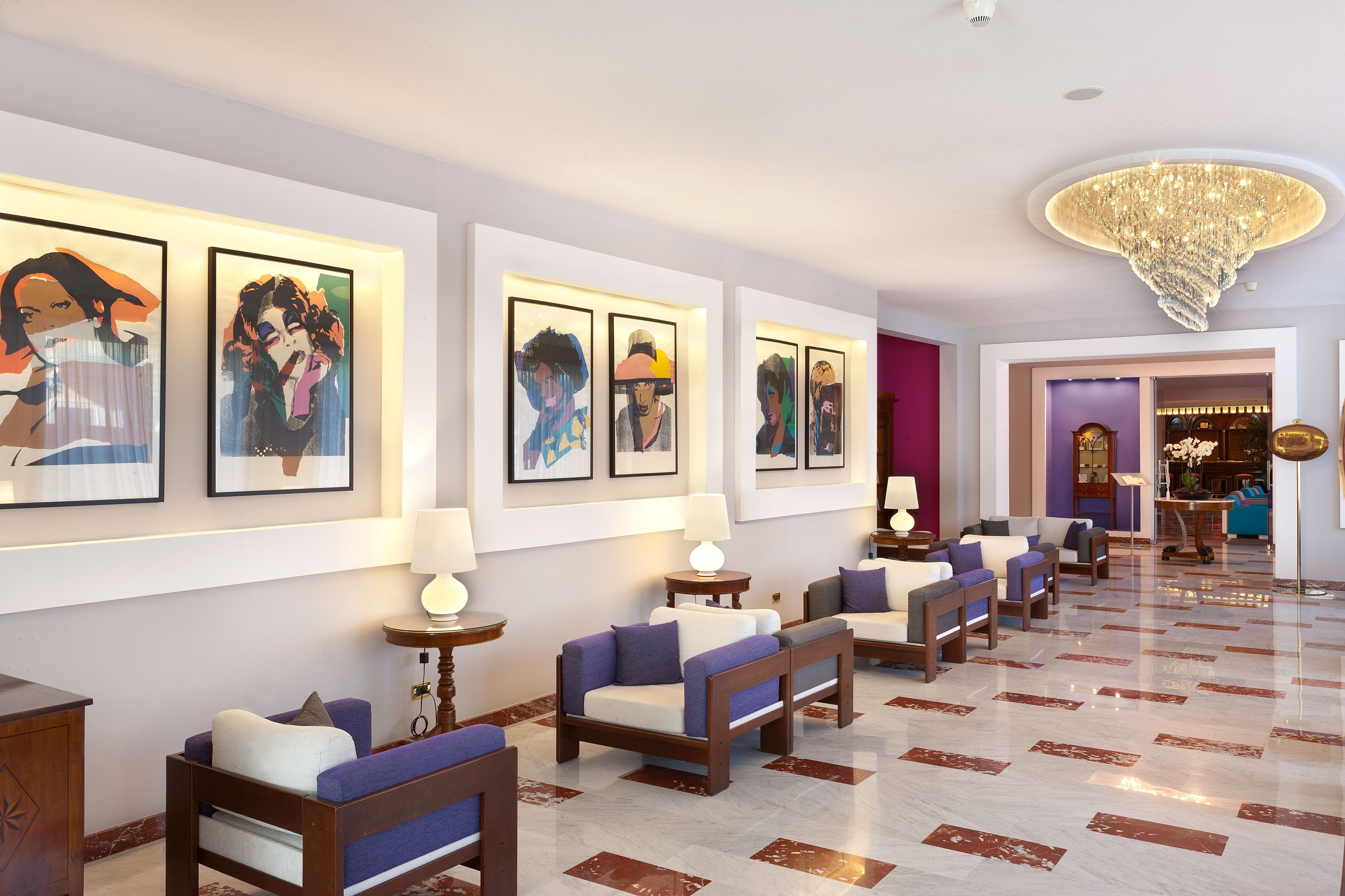 A lobby with a marble floor, sofas, and framed artwork on the walls.