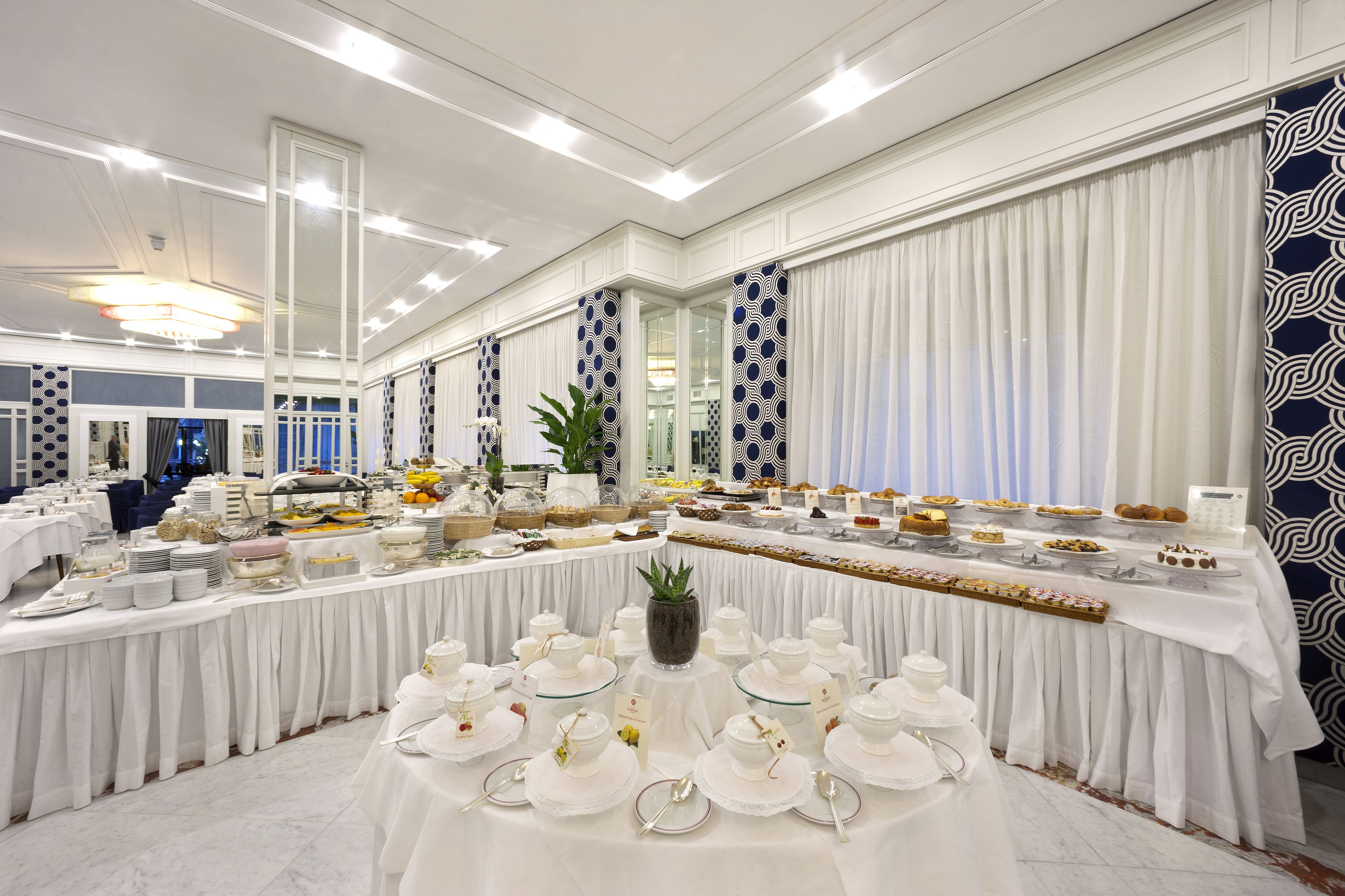 Un salón de banquetes con una larga mesa dispuesta para un evento formal, que incluye una variedad de platos y un arreglo floral central.