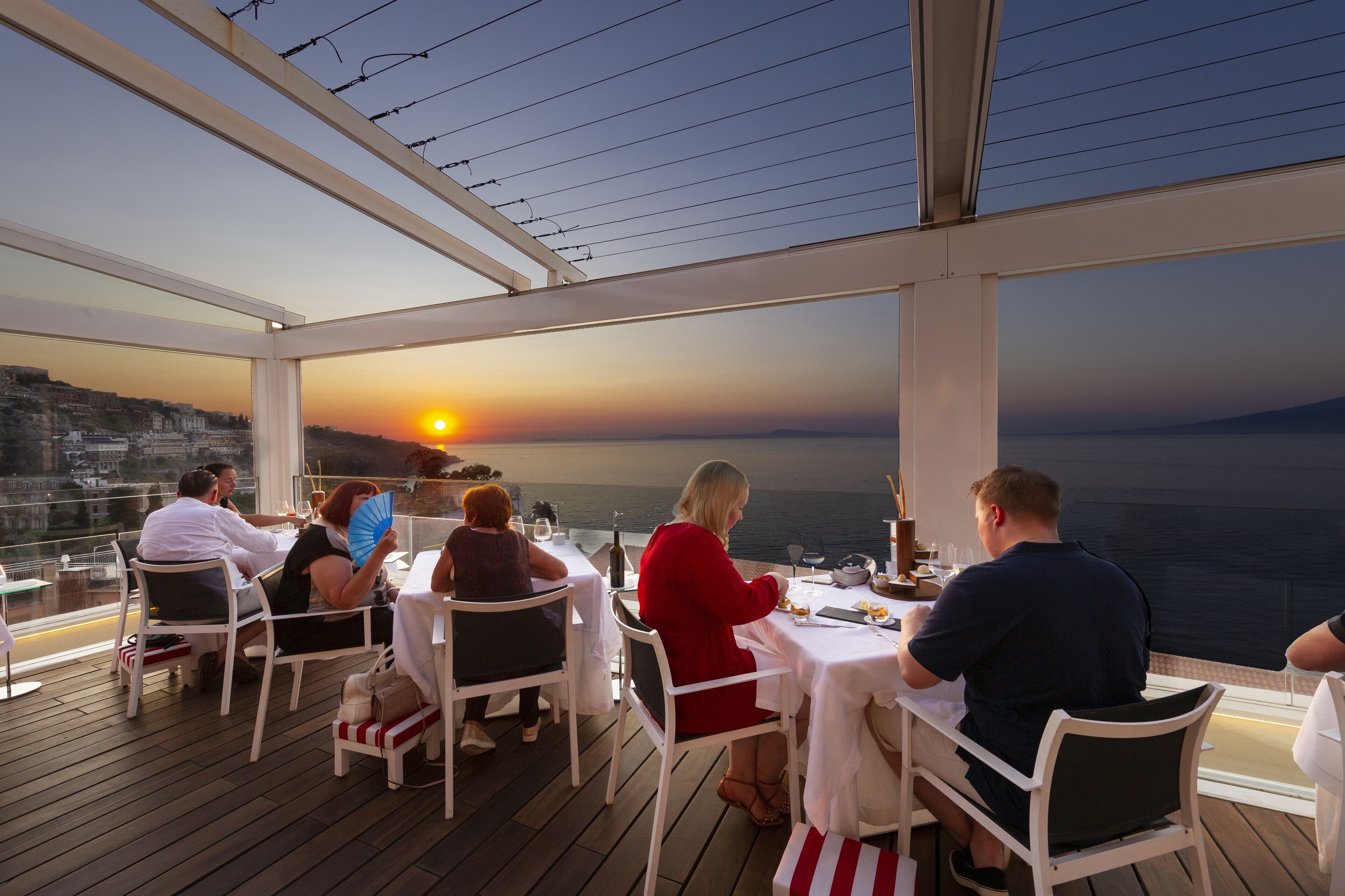 Restaurante com área externa, vista para o pôr do sol e para o mar.