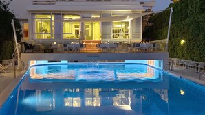 Un hotel moderno con piscina, zona de comedor al aire libre e interior bien iluminado.