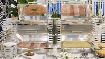 A buffet setup with various food items in clear containers, including meats and cheeses, arranged on a table with plates and utensils.