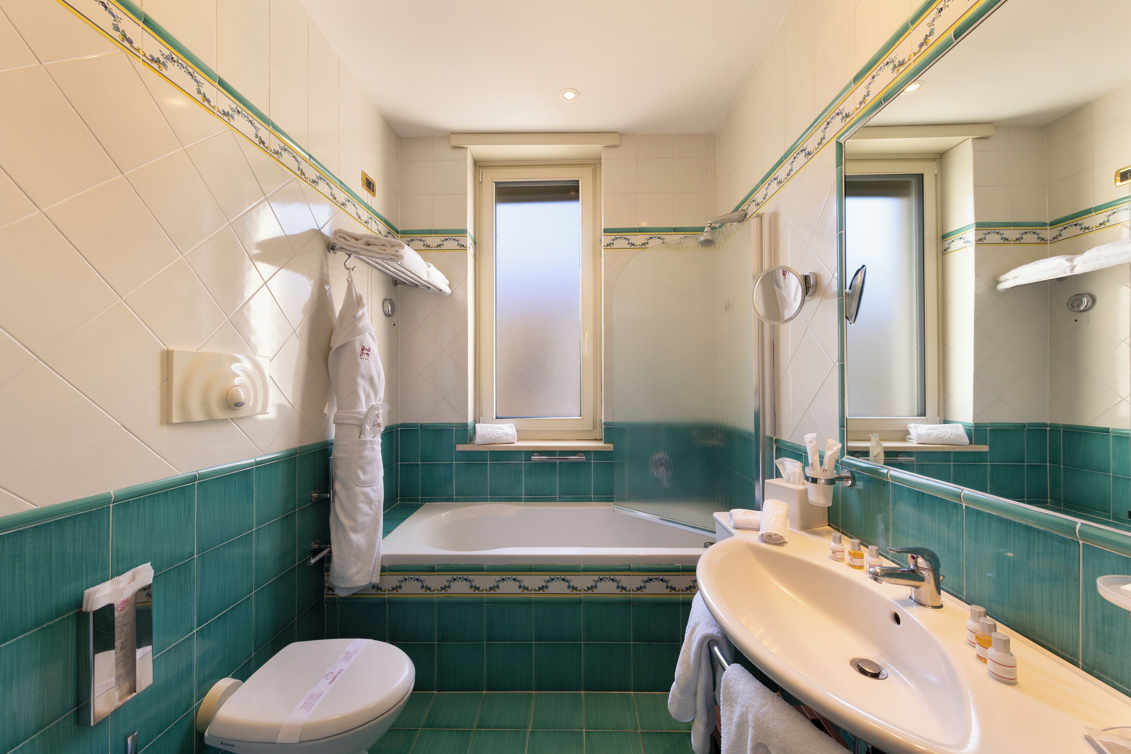 Une salle de bain avec une baignoire, des toilettes, un lavabo et un grand miroir.