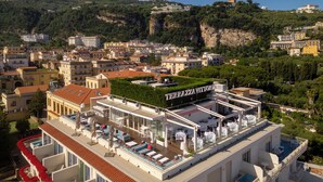 Un hotel con terraza en la azotea, con mobiliario exterior y una piscina.