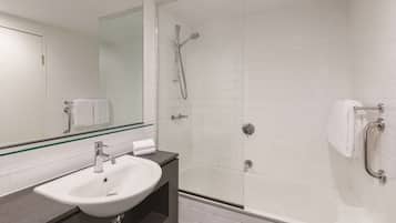Un baño moderno con ducha envuelta en vidrio, un lavamanos blanco y un espejo grande.