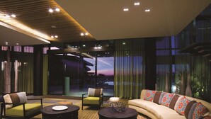 Et moderne loungeområde med sofa, lænestole, skamler og et mønstret gulv.
