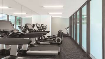 Un gimnasio moderno con cintas de correr, elípticas y bicicletas estáticas.