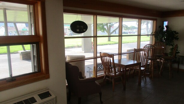 A dining area with a table and chairs, large windows, and a view of the outside. - Motel 6 Prairie Du Chien, WI (Prairie Du Chien)