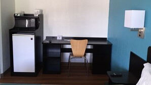 A compact hotel room with a kitchenette, a desk, a chair, a bed, and a nightstand. - Motel 6 Prairie Du Chien, WI (Prairie Du Chien)