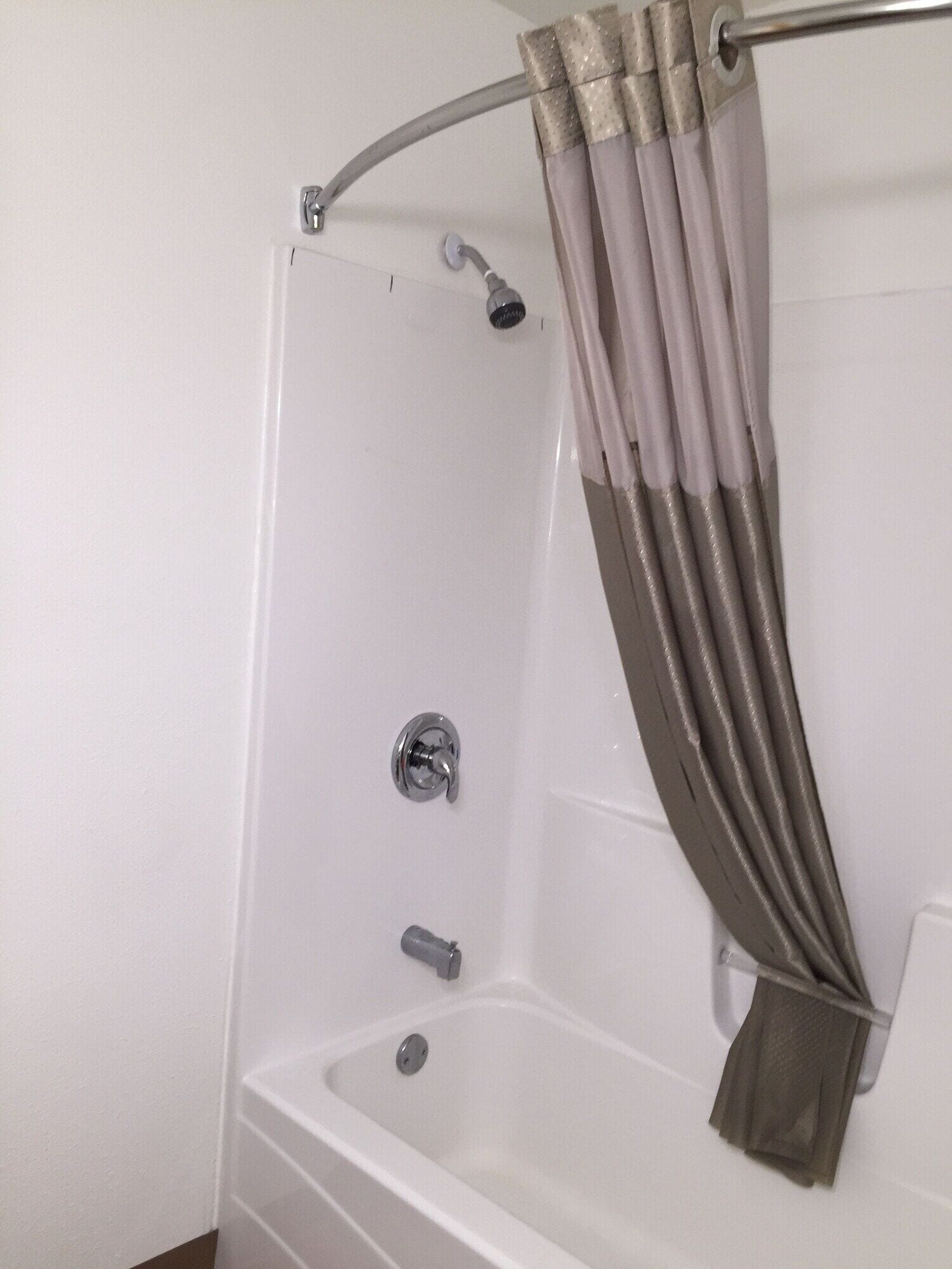 A white bathtub with a showerhead and a curtain rod.