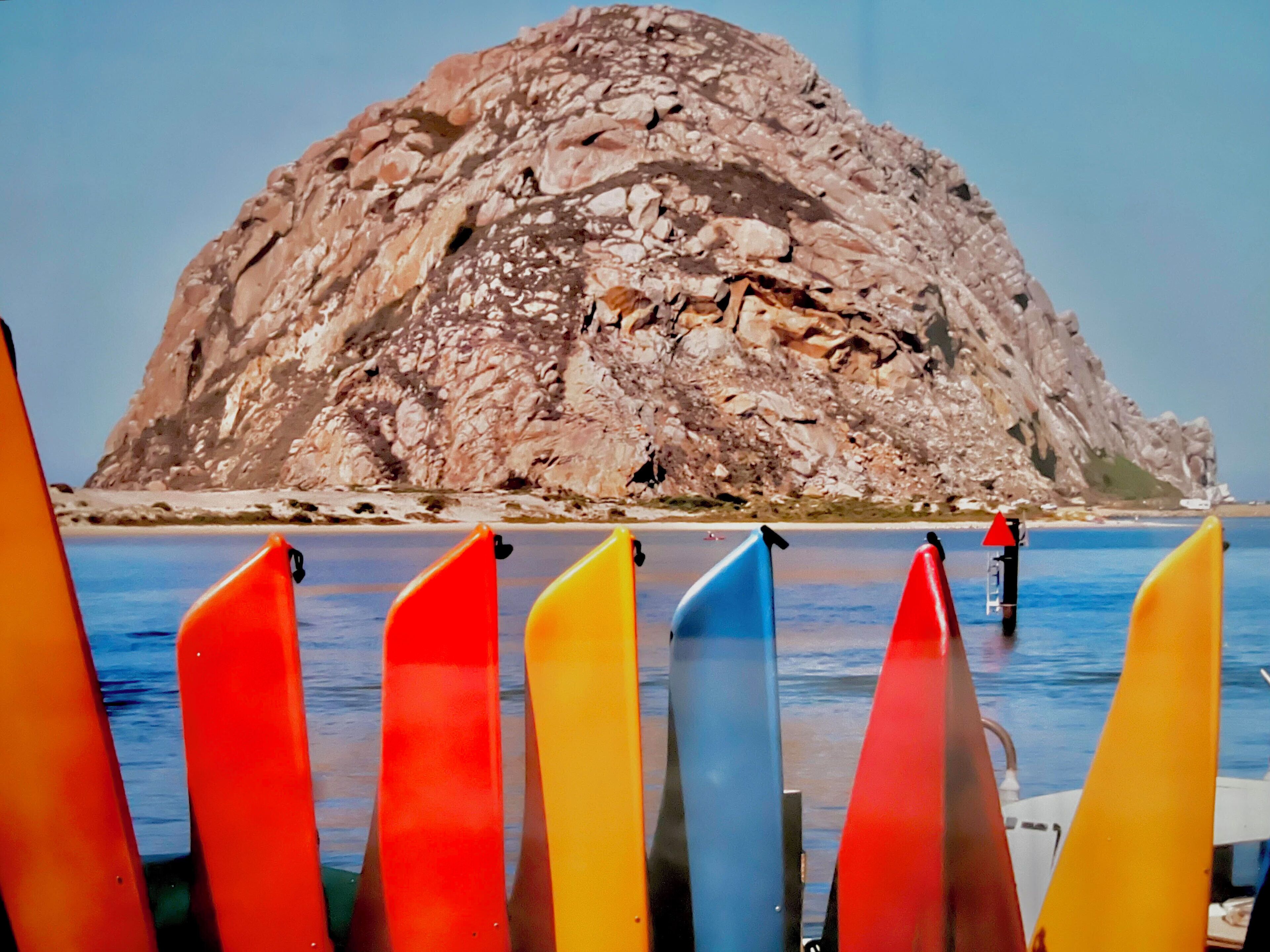Une île rocheuse offrant une vue dégagée sur la mer, avec plusieurs kayaks colorés alignés au premier plan.