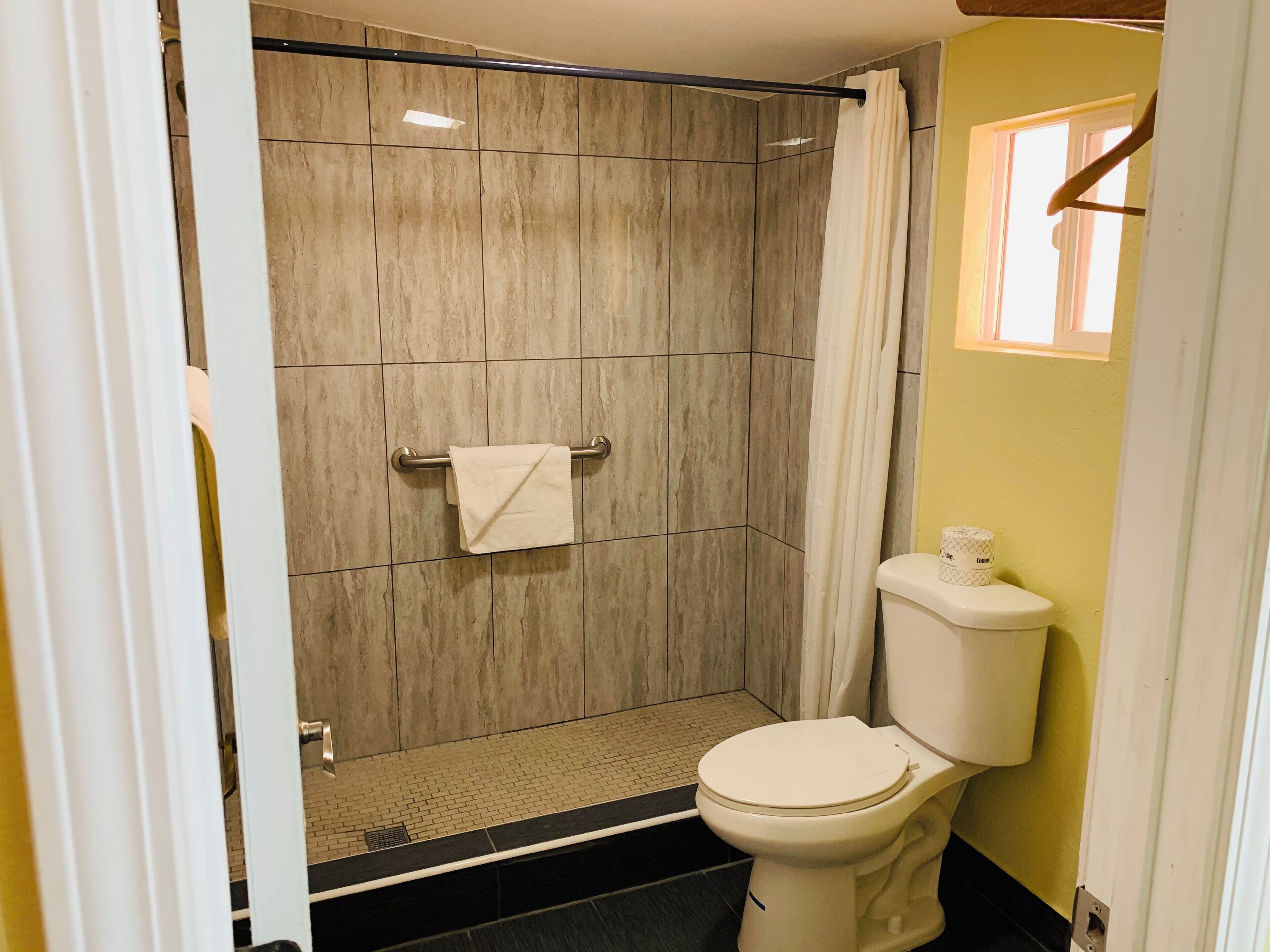 A bathroom with a shower, toilet, and a towel rack.