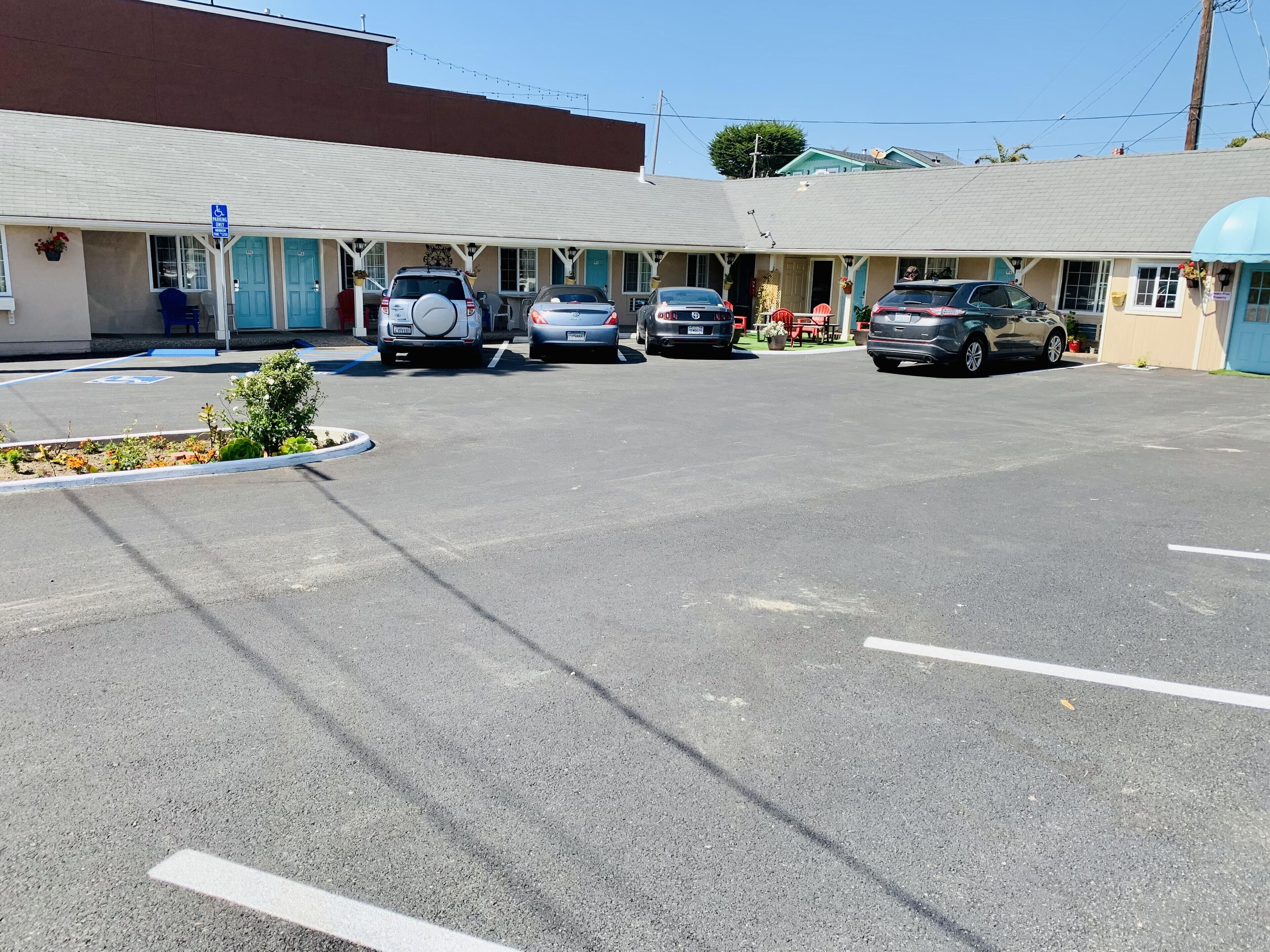 A motel with a parking lot, several cars parked, and a blue handicapped parking sign.