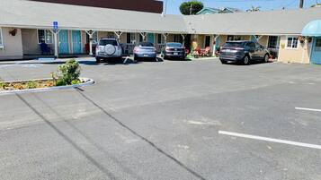 A motel with a parking lot, several cars parked, and a blue handicapped parking sign.