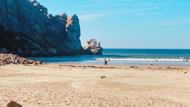 Una playa con acantilados rocosos y cielo despejado.