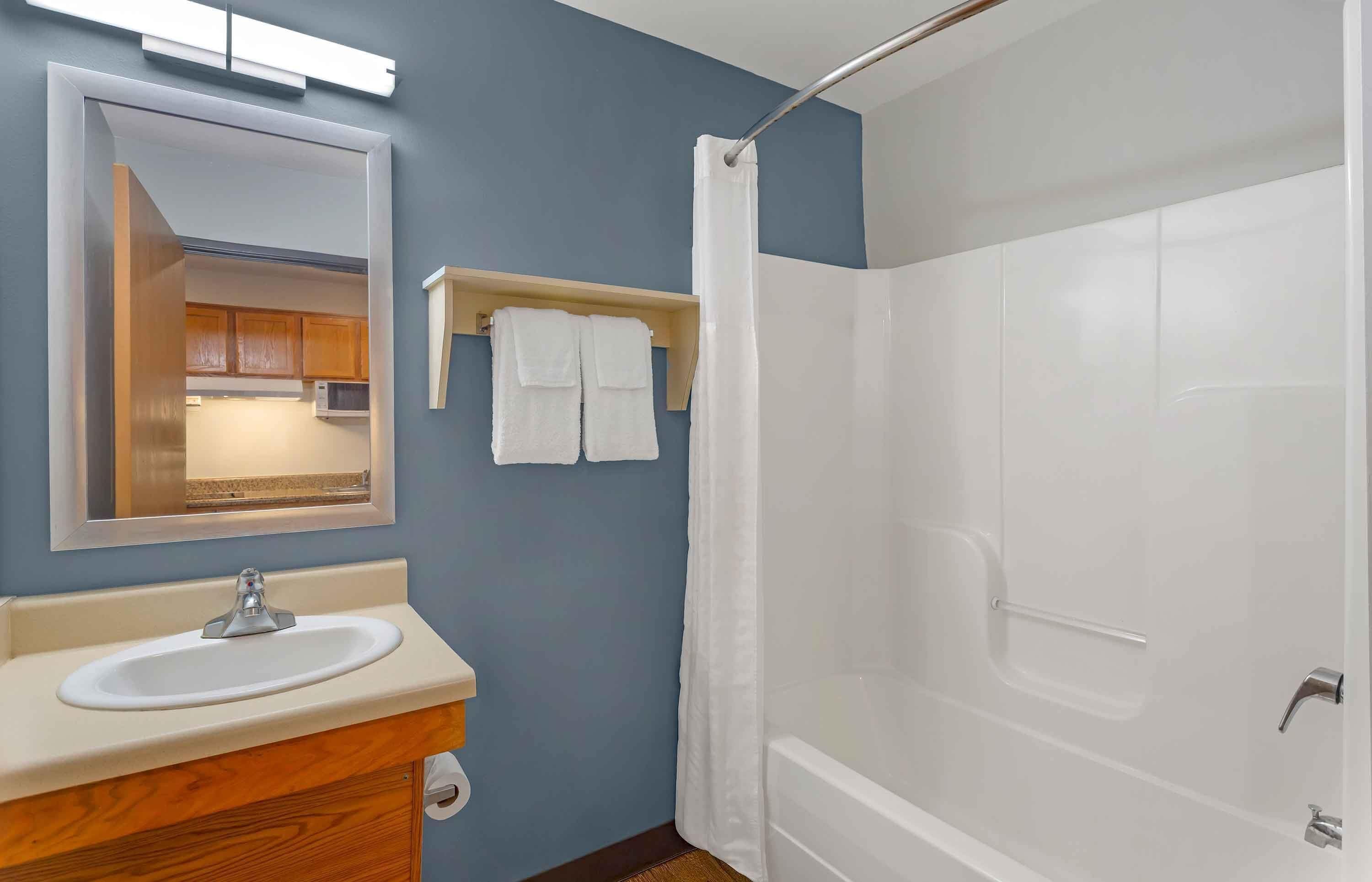 A bathroom with a white sink, mirror, and shower curtain.