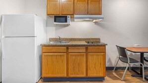 Eine kompakte Küche mit Holzausstattung, einer Mikrowelle, einem Backofen und einem Essbereich mit Tisch und Stühlen.
