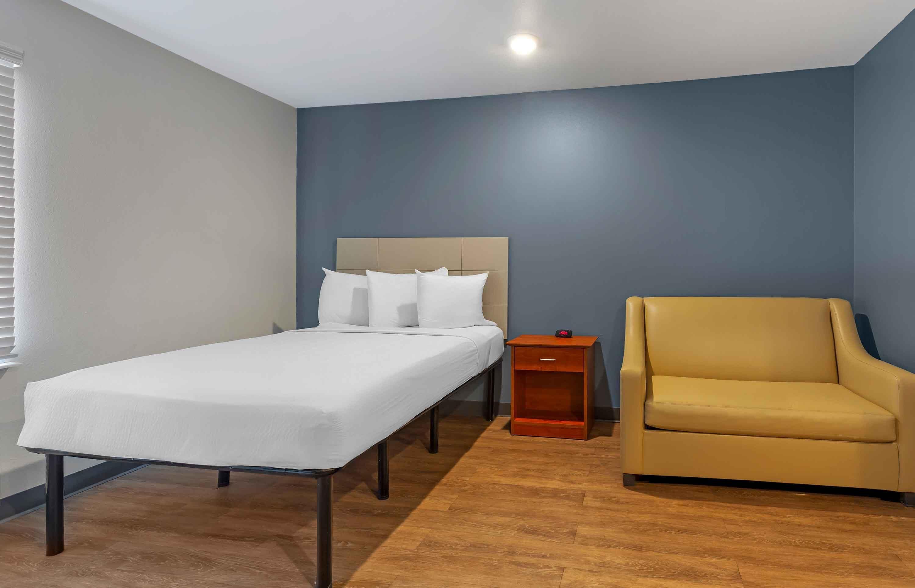 Un dormitorio con una cama individual, una mesita de noche y un sillón amarillo.