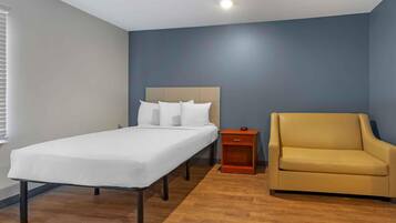 Un dormitorio con una cama individual, una mesita de noche y un sillón amarillo.