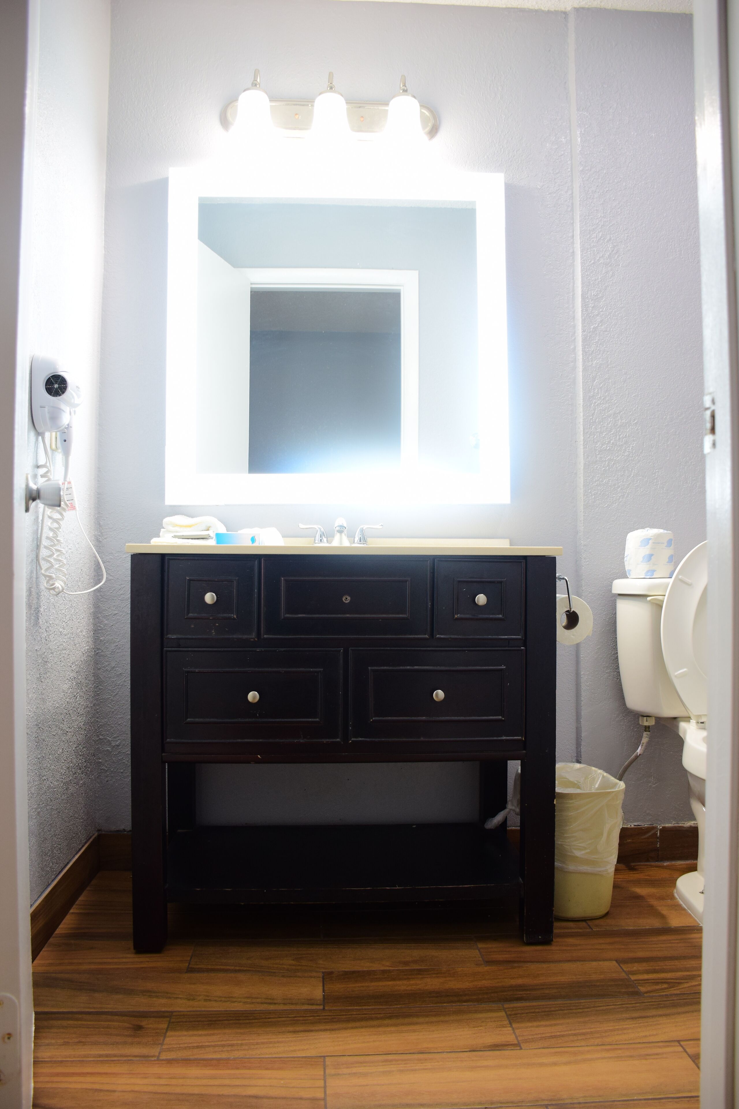 A bathroom with a vanity, mirror, and toilet.