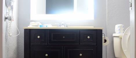 A bathroom with a vanity, mirror, and toilet.