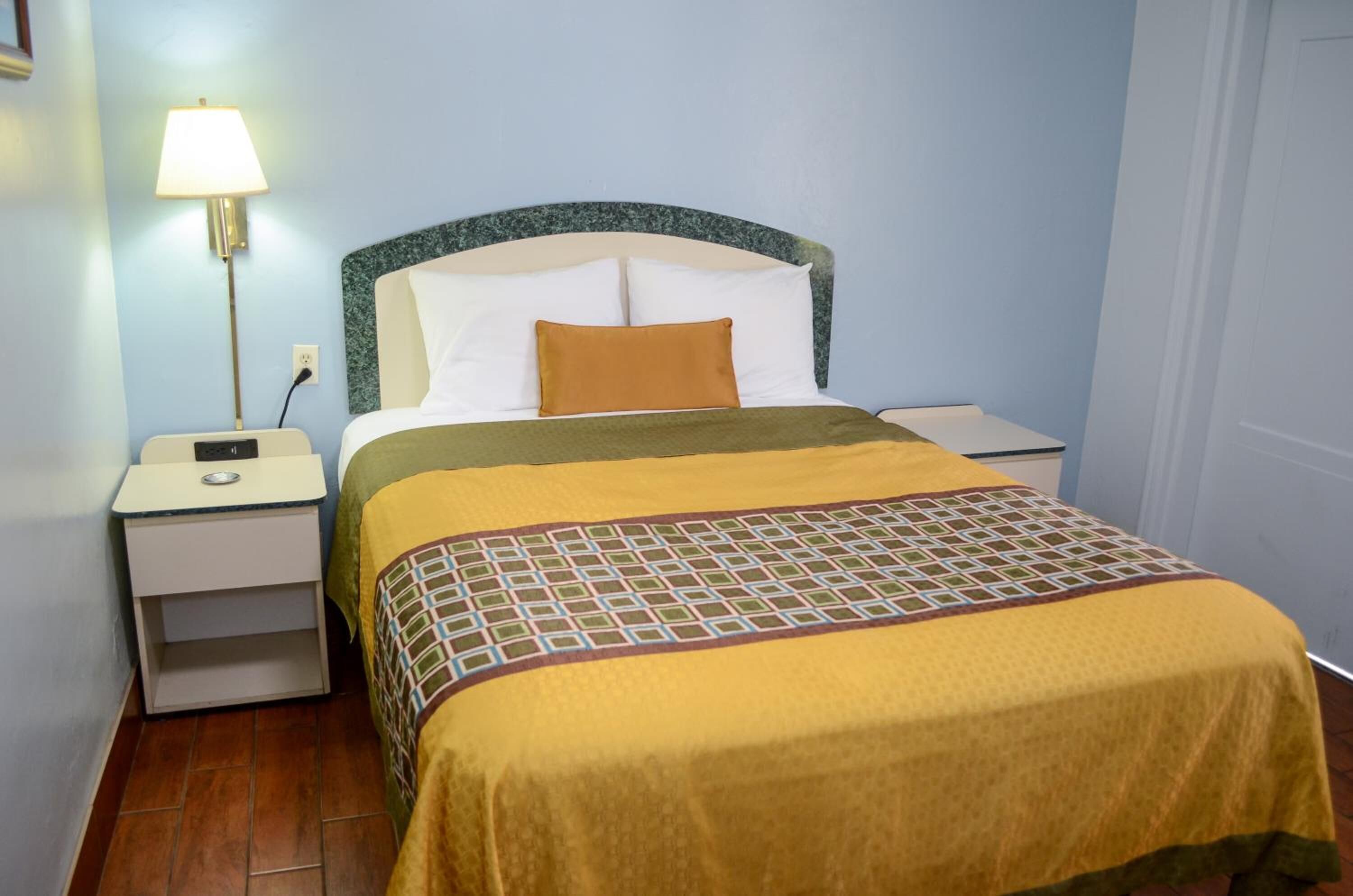 Een hotelkamer met een bed, nachtkastjes, een lamp en een stopcontact.
