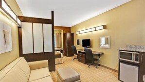 A hotel room with a sofa, a desk, a chair, a small kitchenette, and a TV. - Microtel Inn & Suites by Wyndham Bryson City (Bryson City)