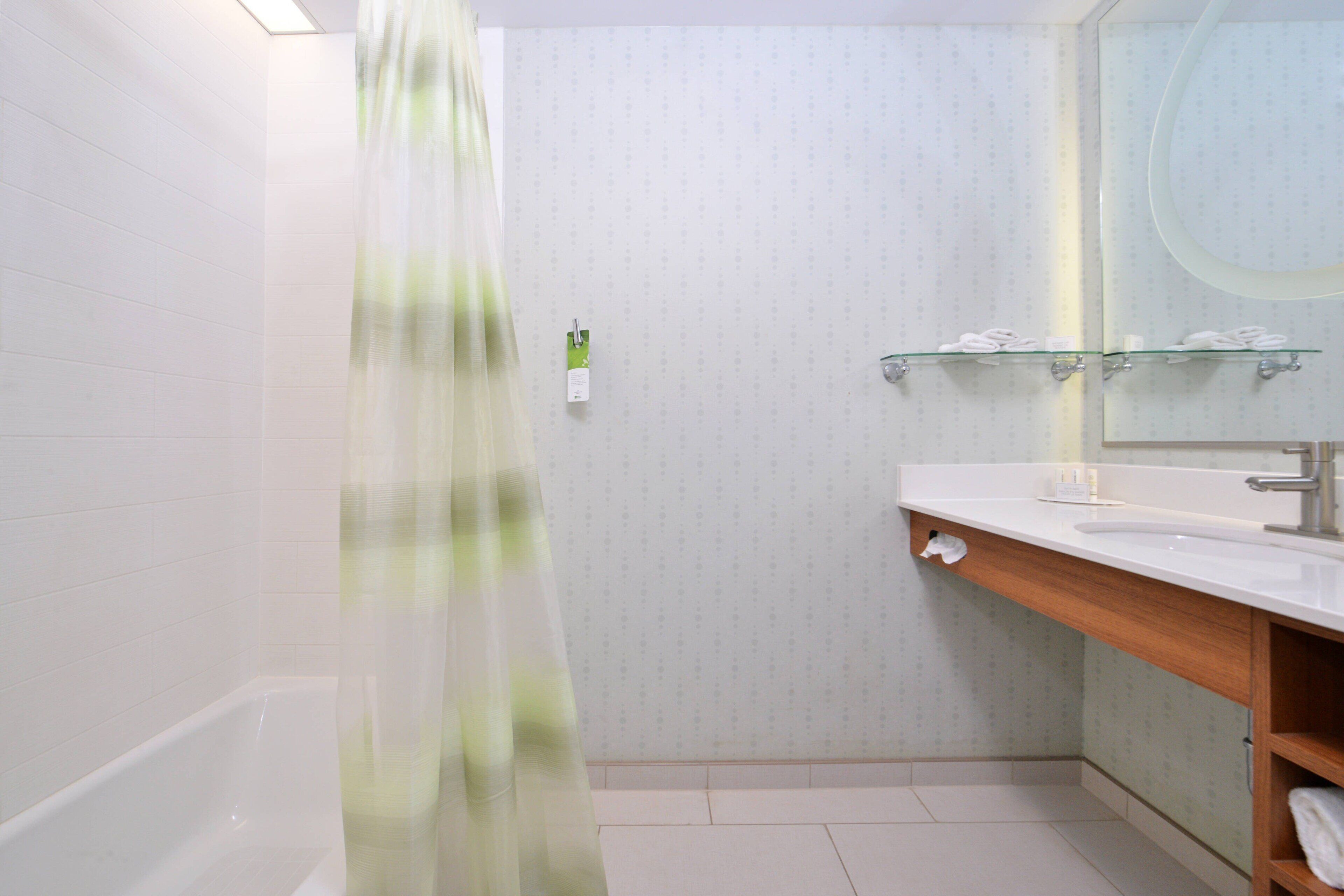 Un baño moderno con bañera, cabina de ducha de vidrio, tocador de madera con espejo y un perchero para toallas.