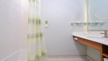 Un baño moderno con bañera, cabina de ducha de vidrio, tocador de madera con espejo y un perchero para toallas.