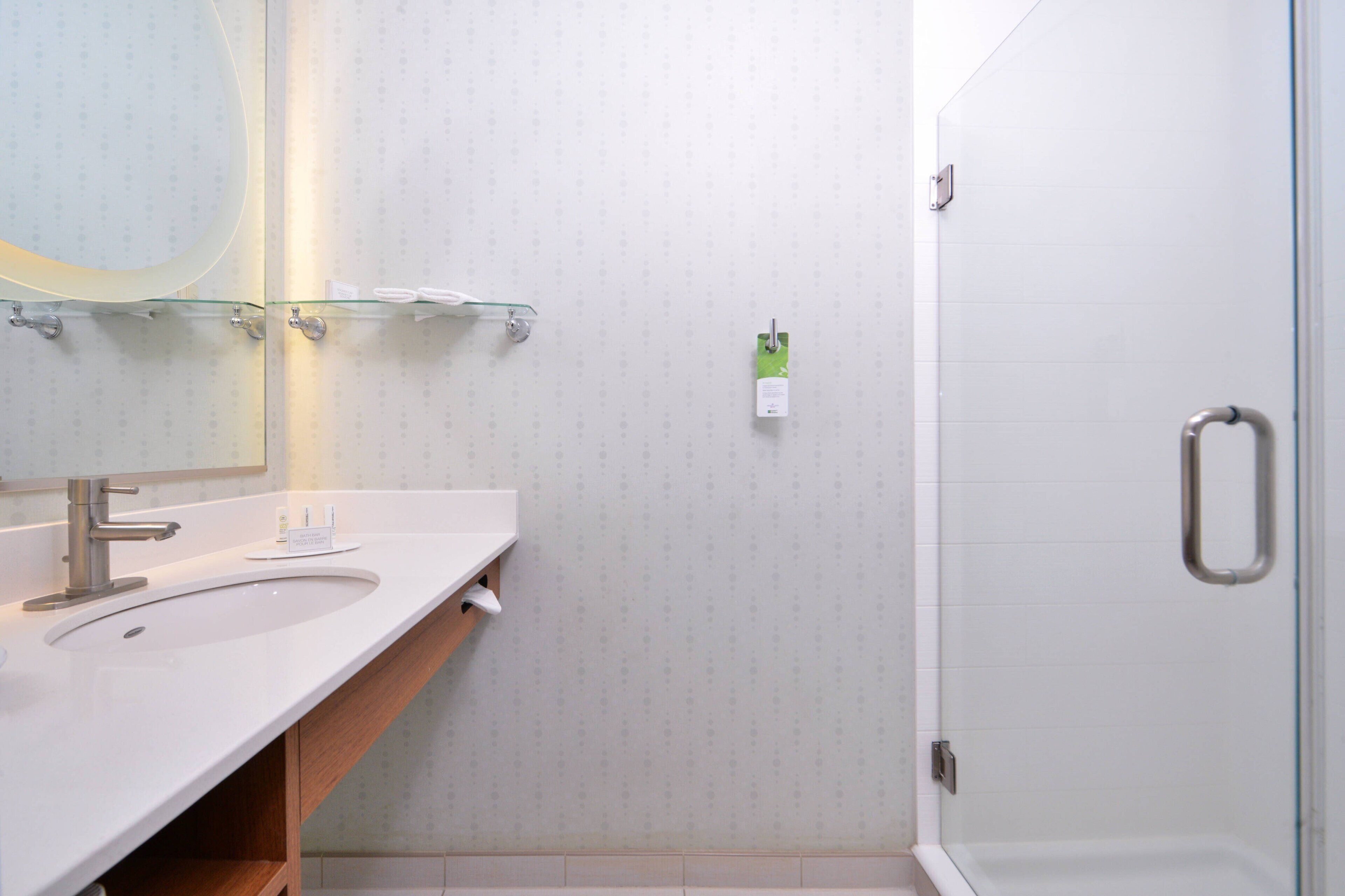 Une salle de bain équipée d’un lavabo, d’un miroir et d’une douche à parois en verre.