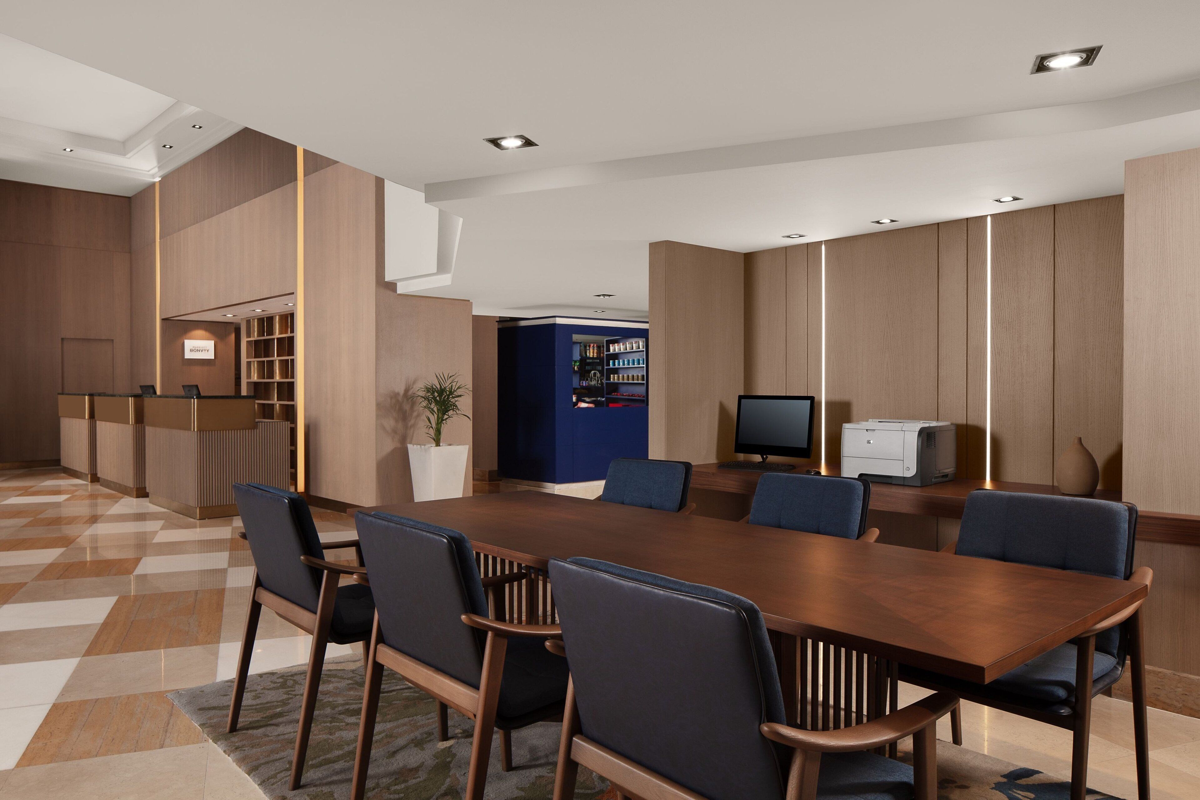 A modern conference room with a wooden table, blue chairs, and a reception desk.