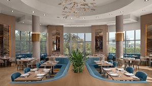 A modern restaurant with a central seating area, large windows, and a unique ceiling design. - Delta Hotels Istanbul West (Istanbul)